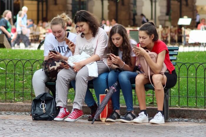 Five young ladies distracted on their phone