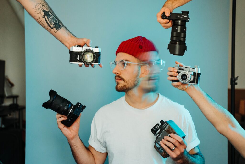 Abstract picture of a man with a red hat surrounded by cameras showing off his creative expression