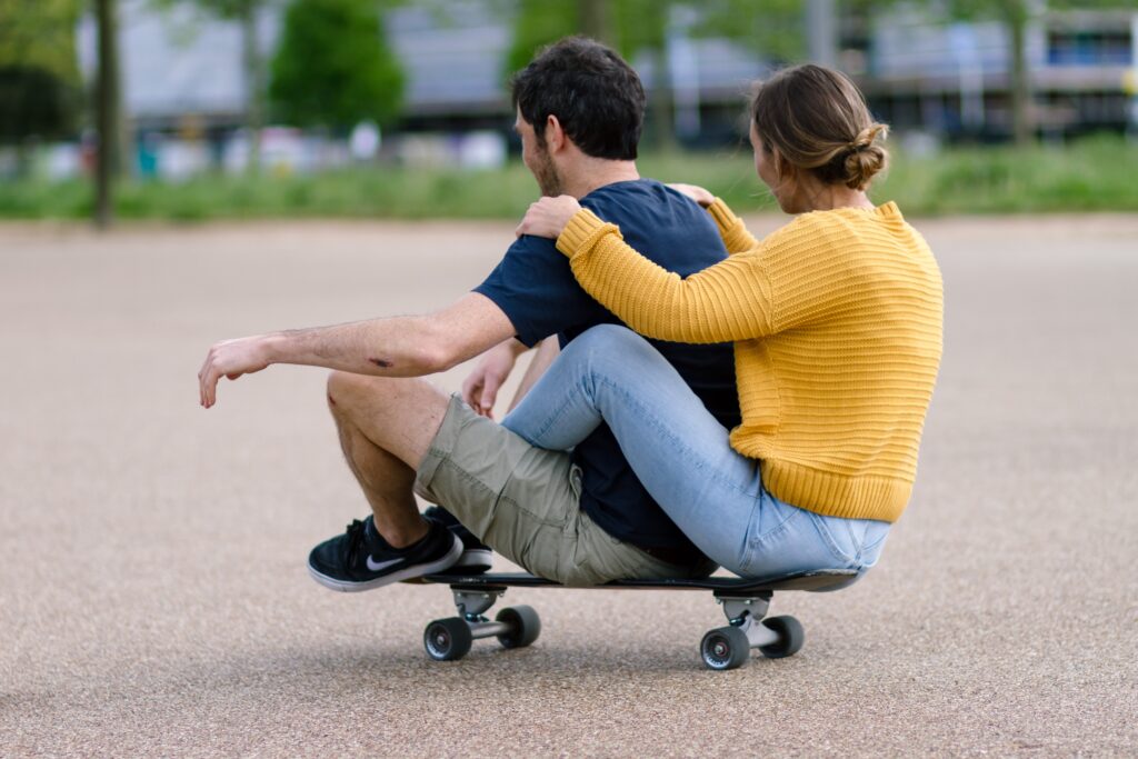 Man and woman riding a skateboard demonstrating trust exercises for couples