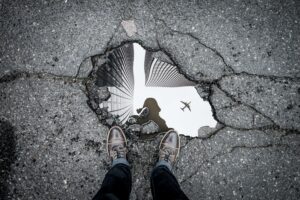 Picture of a person gazing at their year-end reflection as they peer into a buddle beneath their feet.